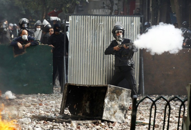 Image: A riot policeman fires a shotgun at protesters during clashes at a side street near Tahrir Square in Cairo