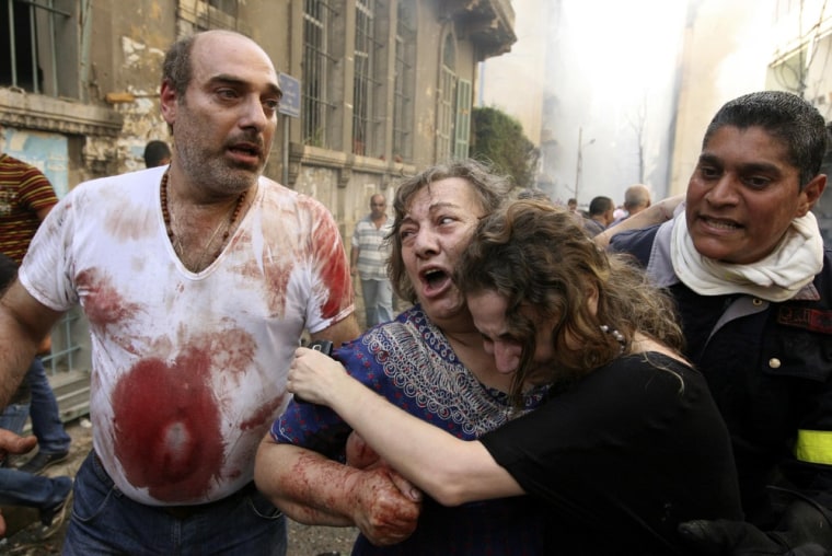 Image: Relatives comfort a wounded woman at the site of an explosion in Ashafriyeh