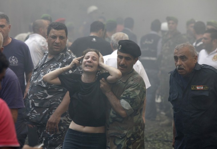 Image: A woman is helped by a Lebanese soldier after an explosion in Ashafriyeh district