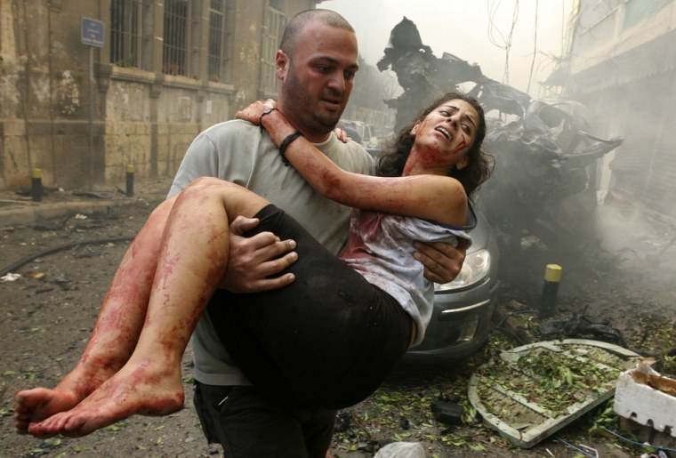 Image: A wounded woman is carried at the site of an explosion in Ashrafieh