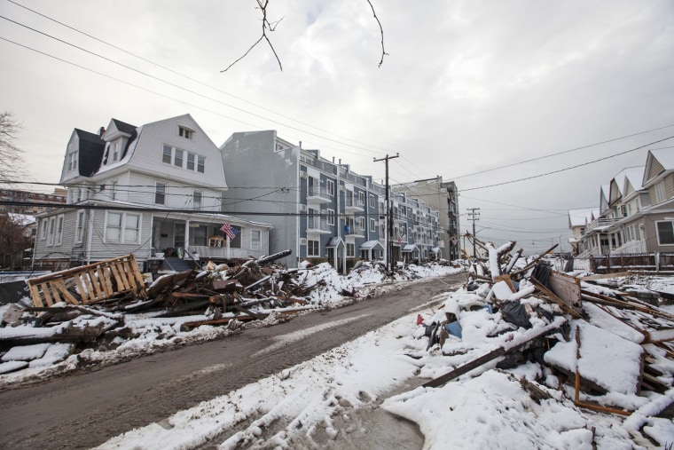 Image: Snow left by a nor'easter, also known as a northeaster storm, covers piles of debris piled up outside of peoples homes due to the flooding from hurricane Sandy in the Queens borough neighborhood of Rockaway Beach
