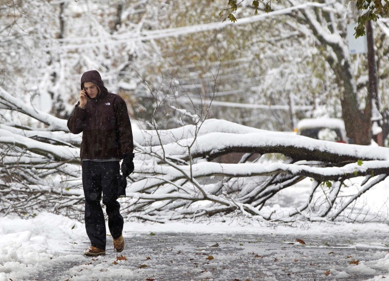 Image: A man walks down a street past a snow covered fallen tree in Roslyn Heights, New York