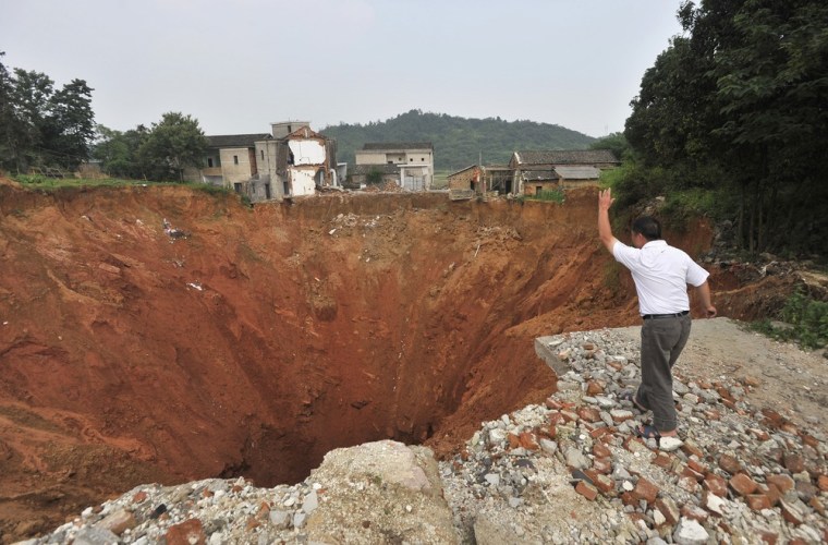 Image: A local resident throws a stone into a sinkhole near Qingquan primary school in Dachegnqiao town of Ningxiang