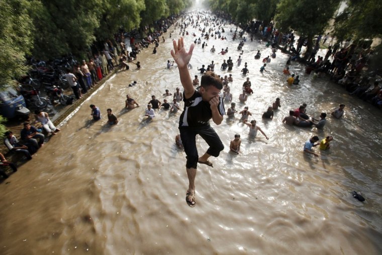 Image: A boy jumps into a water canal to cool himself with others on a hot day in the eastern city of Lahore