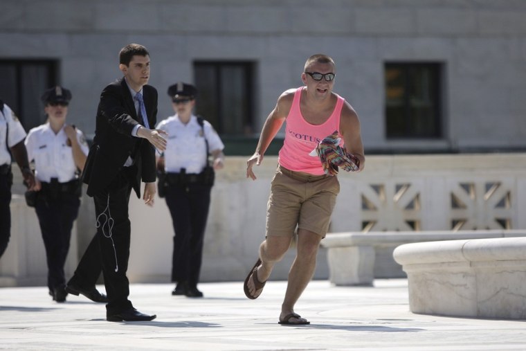 Image: A man in a pink tank top runs with the printed copy of the U.S. Supreme Court's ruling against the federal Defense of Marriage Act (DOMA), outside the court in Washington