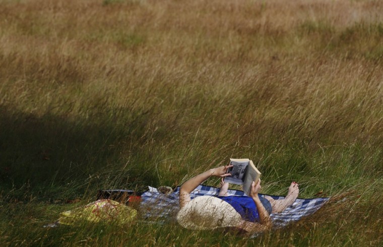 Image: A woman reads a book in Richmond Park in southwest London