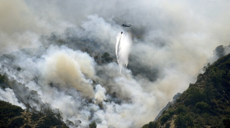 Image: A helicopter drops water on the Morgan fire as it advances down a rugged hillside at Mount Diablo State Park near Clayton