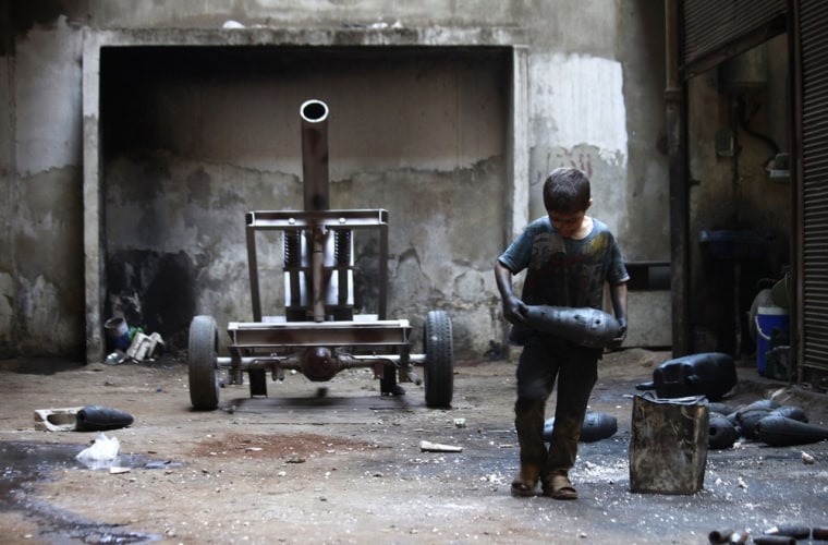 Image: Issa carries a mortar shell in a weapons factory of the Free Syrian Army in Aleppo