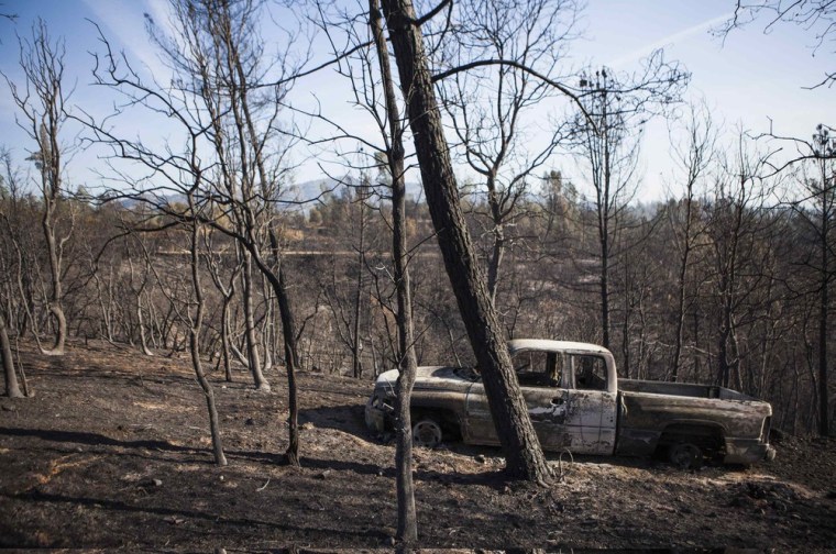 Image: A truck burned by the Clover Fire is seen amongst trees in Happy Valley, California