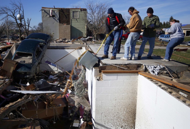 Image: Martin pushes a safe out of his neighbors' basement as other neighbors pull from above in Washington