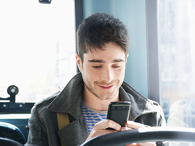 Image: Man texting and smiling on bus
