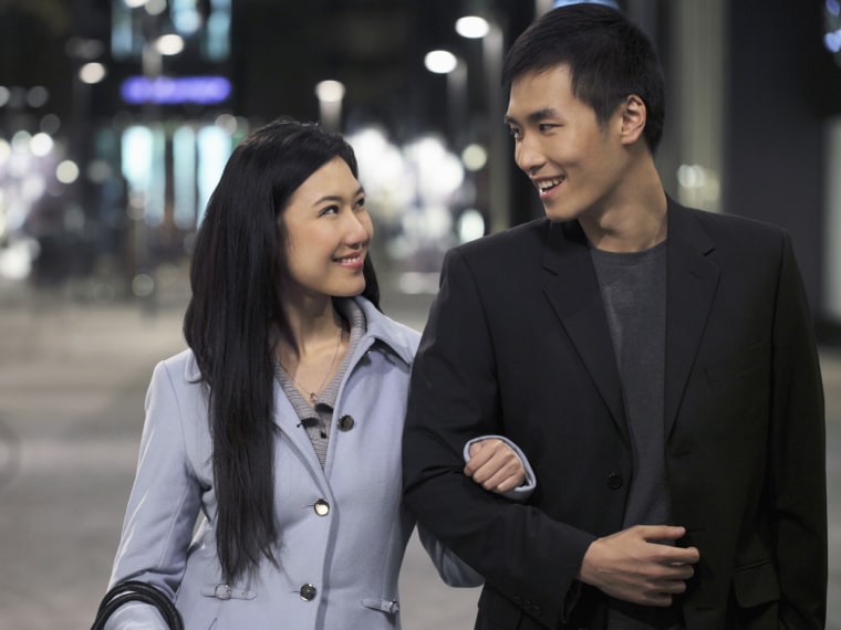 Young couple wearing coats walking on the street at night