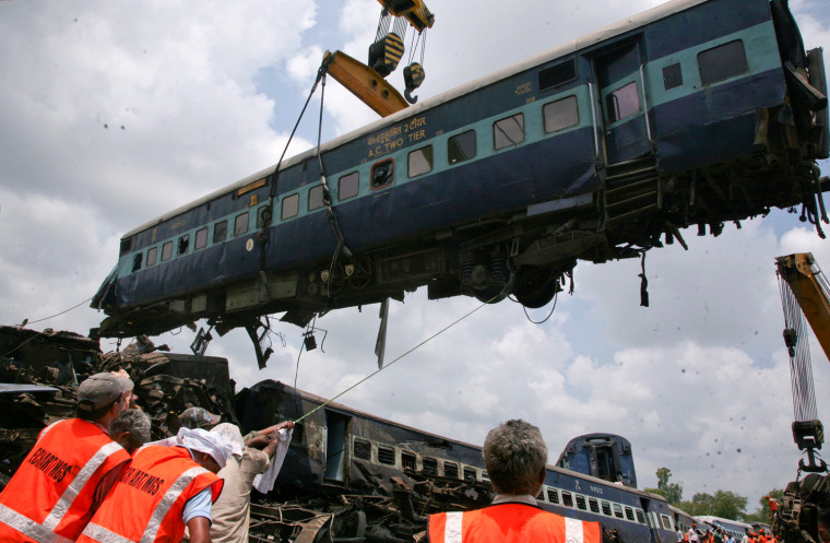 Image: Rescue workers help to move a carriage lifted by crane from a passenger train which derailed near Fatehpur