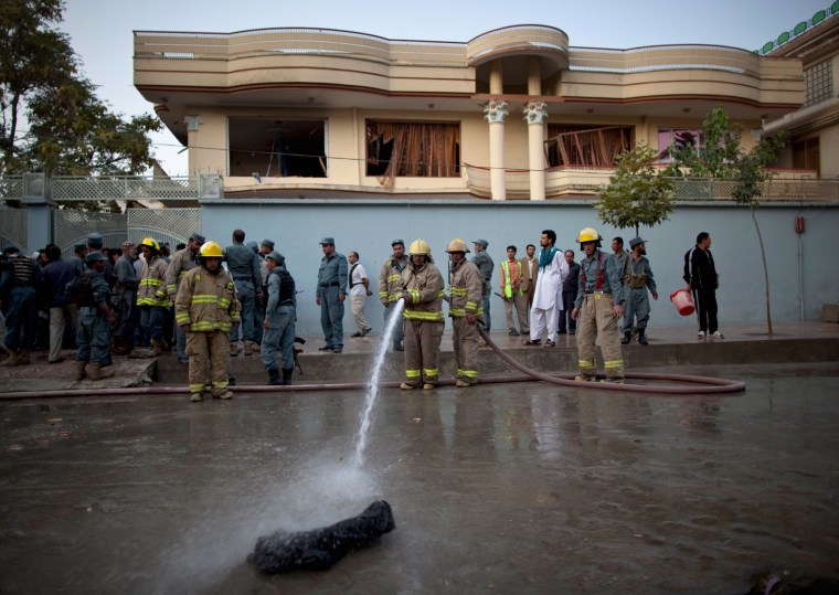 Image: Afghan firefighters hose down area in front of house of Khan, who was killed by armed gunmen during Sunday's attack, in Kabul