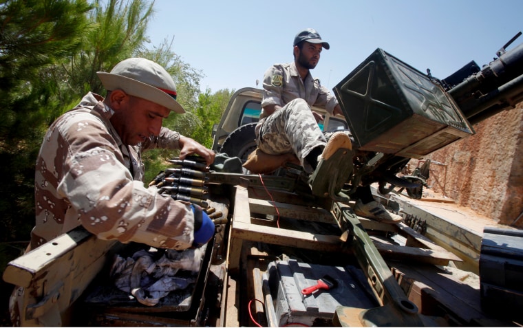 Image: Libyan rebels clean ammunition for an anti-aircraft gun at a front line checkpoint near Tiji