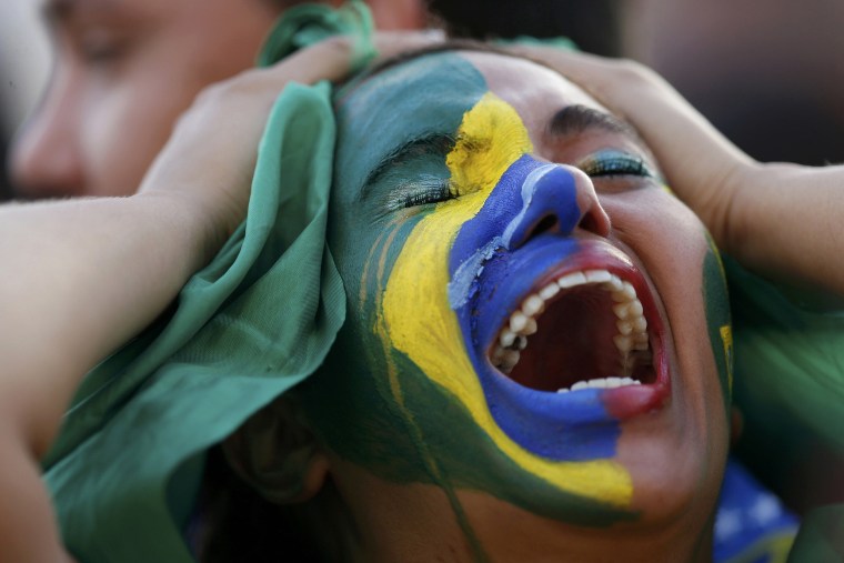 Image: Fans of Brazil react while watching a broadcast of the 2014 World Cup semi-final against Germany at the Fan Fest in Brasilia