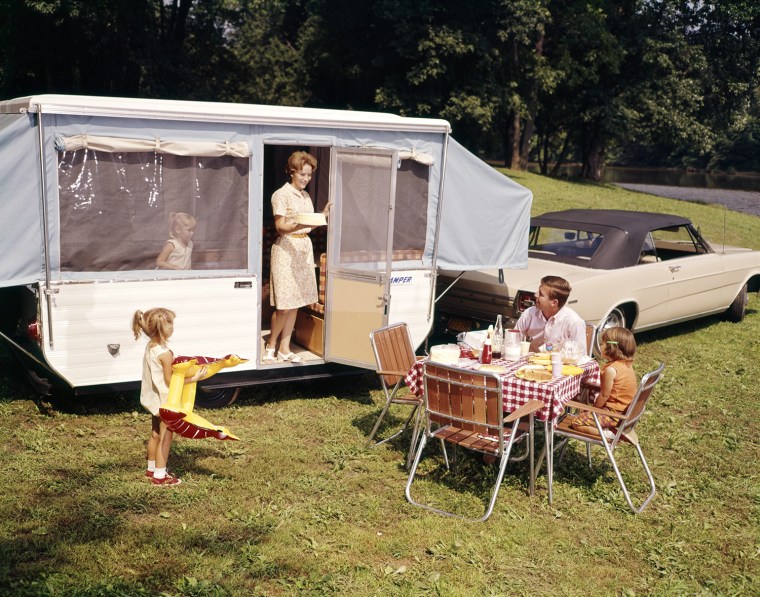 1960s FAMILY WITH THREE DAUGHTERS AT TABLE BY AUTOMOBILE AND TRAILER FIVE EATING FOOD VACATION MAN WOMAN GIRL. H. ARMSTRONG ROBERTS/CLASSICSTOCK/Everett Collection (kc3535)