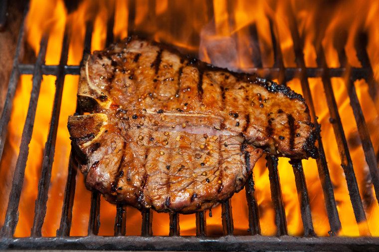 A t- bone steak flame broiled on a barbecue, shallow depth of field.