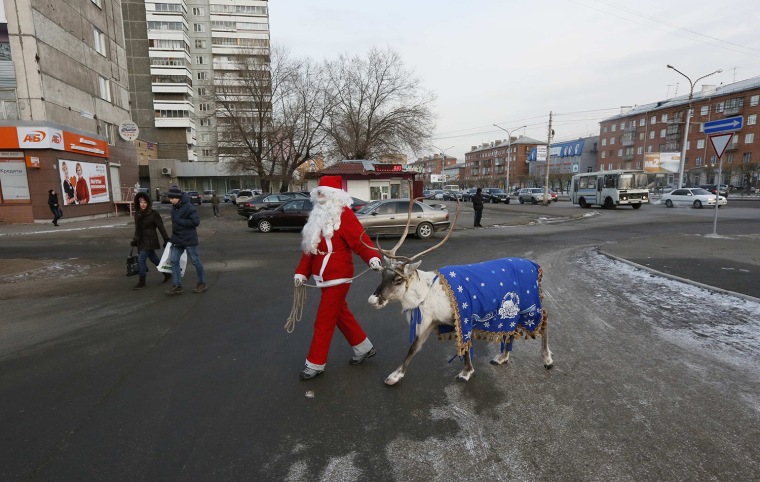 Image: An employee of a local zoo dressed as Santa Claus walks with a reindeer and meets with local residents while marking the upcoming Christmas and New Year's celebrations in Krasnoyarsk