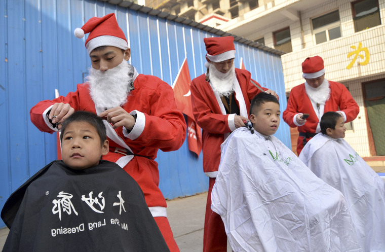 Image: Volunteers in Santa Claus costumes give free hair cuts to children at a welfare house to celebrate the upcoming Christmas festivities in Handan