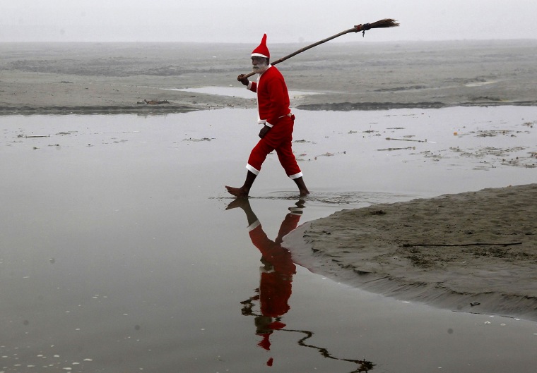Image: Hindu devotee wearing a Santa Claus costume walks after cleaning a part of the banks of the river Ganges in the northern Indian city of Allahabad