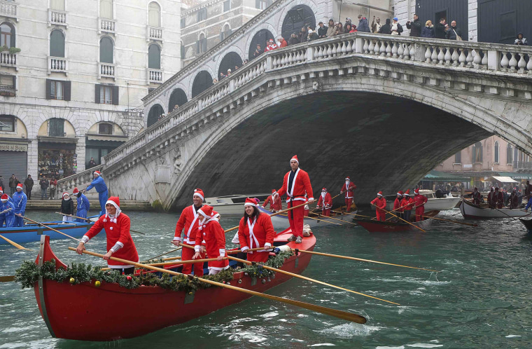 Image: People dressed as Santa Claus ride their gondolas past the Rialto bridge in Venice
