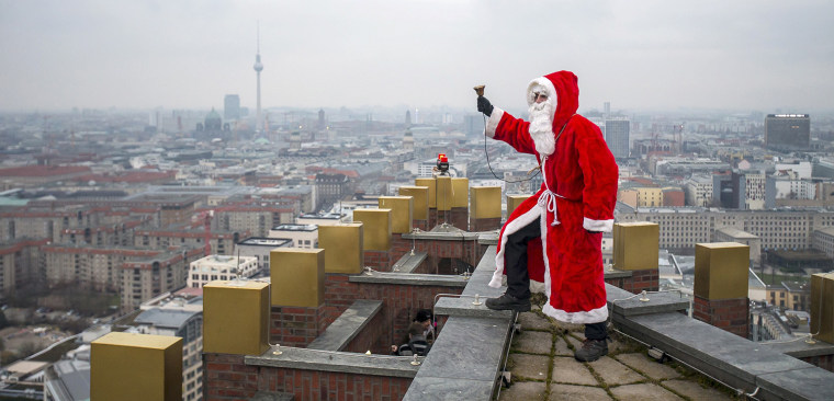 Image: A man dressed a s Santa Claus poses on the roof of the Kollhoff Tower at Potsdamer Platz square in Berlin