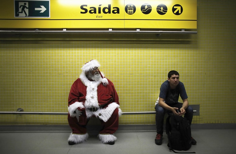 Image: A man, dressed as Santa Claus, waits to board a train at a subway station as part of a promotional event by a bank in Sao Paulo