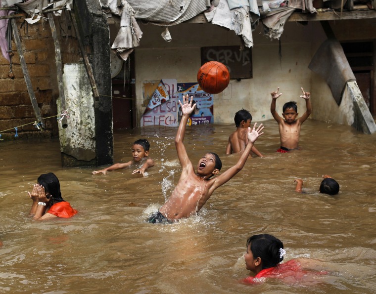 Image: Children play with a ball during a flood near their house in Jakarta