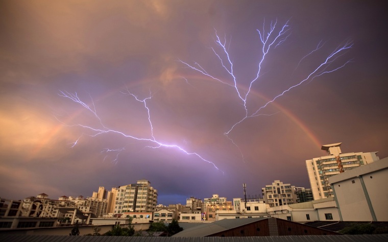 Image: A rainbow is seen in the sky as lightning strikes after a rainstorm in Haikou