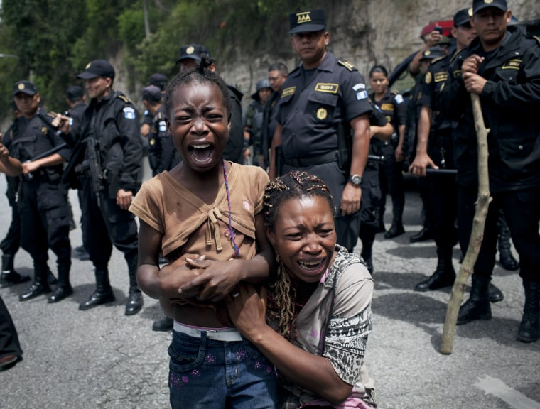Image: Elsy Castillo, 25, and her 8-year-old daughter Dairl, react as they are forced to leave the area near the Jacobo Arbenz housing settlement by the military and police in Guatemala City