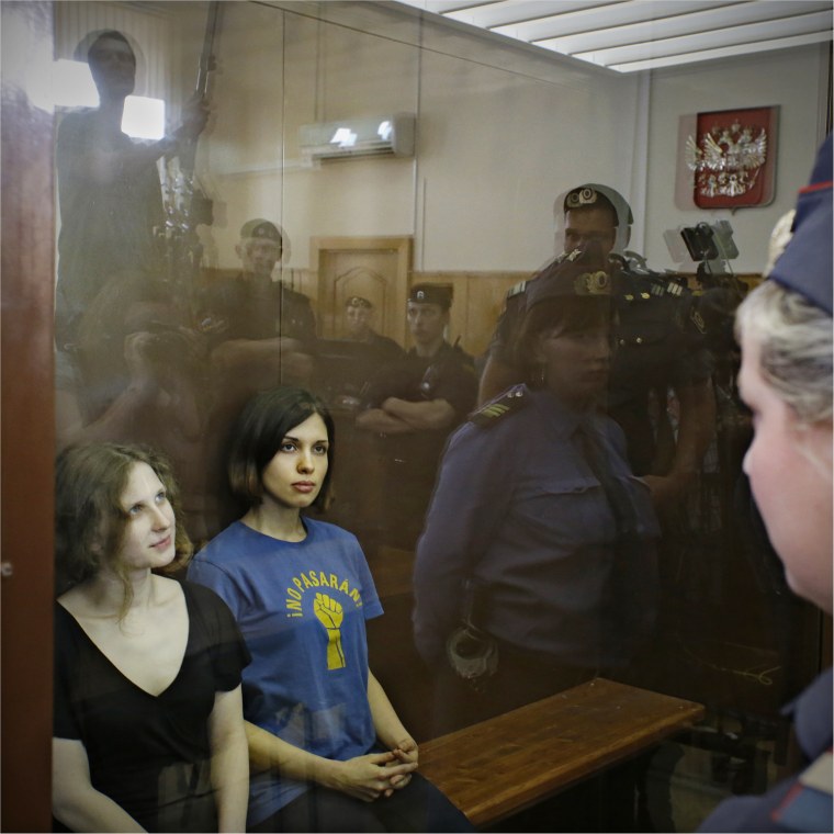 Image: Feminist punk group Pussy Riot members sit in a glass cage at a court room in Moscow