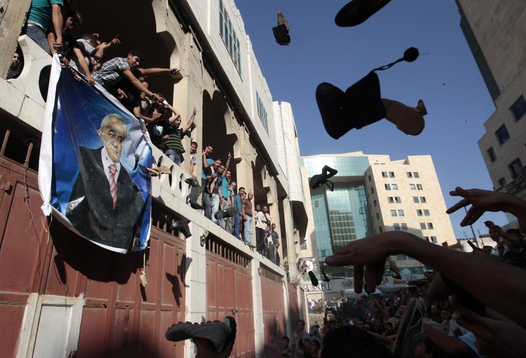 Image: Palestinian protesters throw shoes at a banner of Prime Minister Salam Fayyad during a demonstration against high living costs and the government in the West Bank city of Hebron