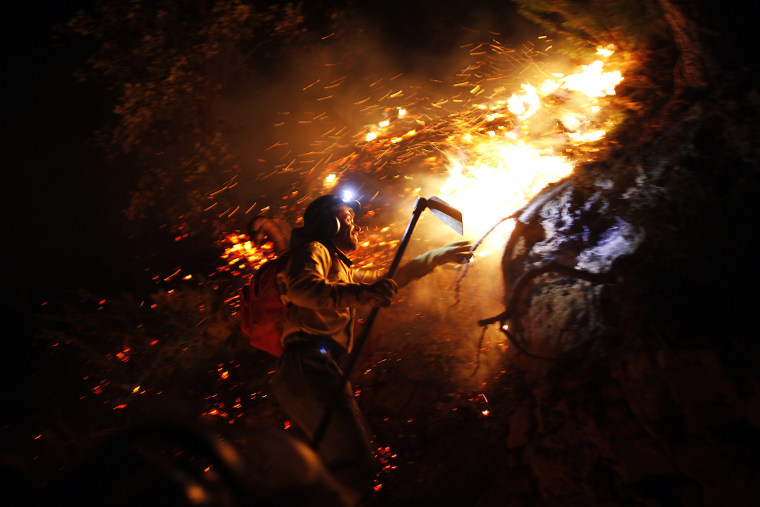 Image: A firefighter climbs a mountain to extinguish a wildfire in Jubrique