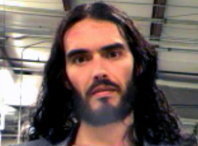 Russell Brand poses for a mugshot in New Orleans after his arrest for allegedly grabbing a photographer's phone and throwing it through a window.