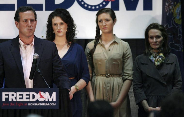 Image: Republican presidential candidate Santorum speaks onstage as his daughters and wife Karen look on during his Illinois primary night rally
