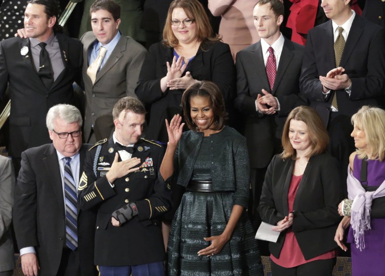 Image: U.S. first lady Michelle Obama (C) waves next to U.S. Army Ranger Sgt. First Class Remsburg prior to President Barack Obama's State of the Union speech on Capitol Hill in Washington