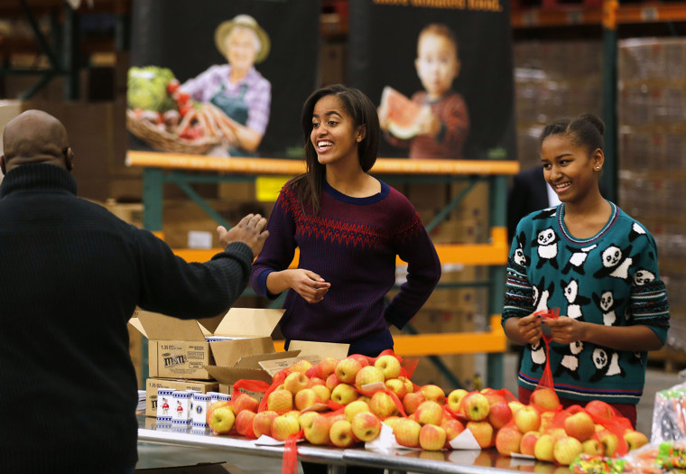 Image: Malia and Sasha, daughters of U.S. President Obama hand out Thanksgiving food at the Capital Area Food Bank in Washington