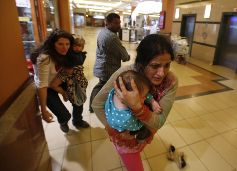 Image: Women carrying children run for safety as armed police hunt gunmen who went on a shooting spree in Westgate shopping centre in Nairobi