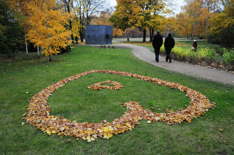 Image: People walk past a heart made of autumna