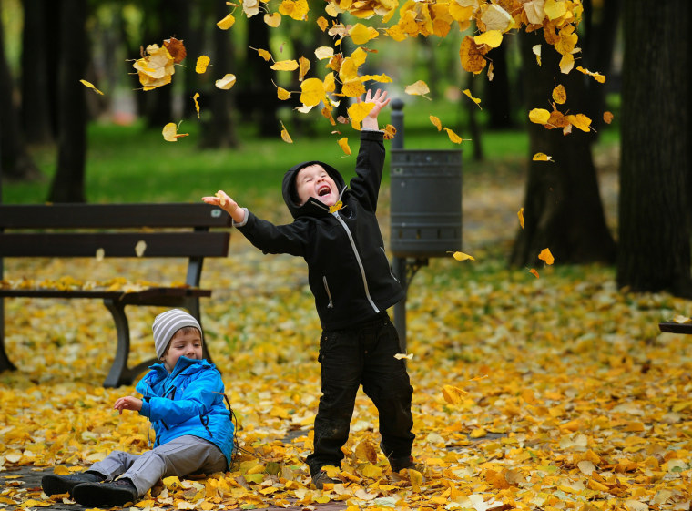 Image: Children play with fallen leaves in a park in Bucharest