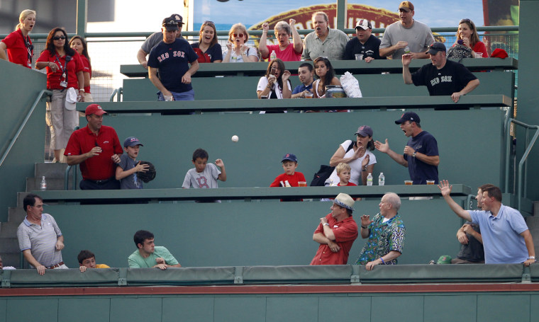 Image: Fans react as a solo home run ball lands in the stands during a MLB American League baseball game in Boston