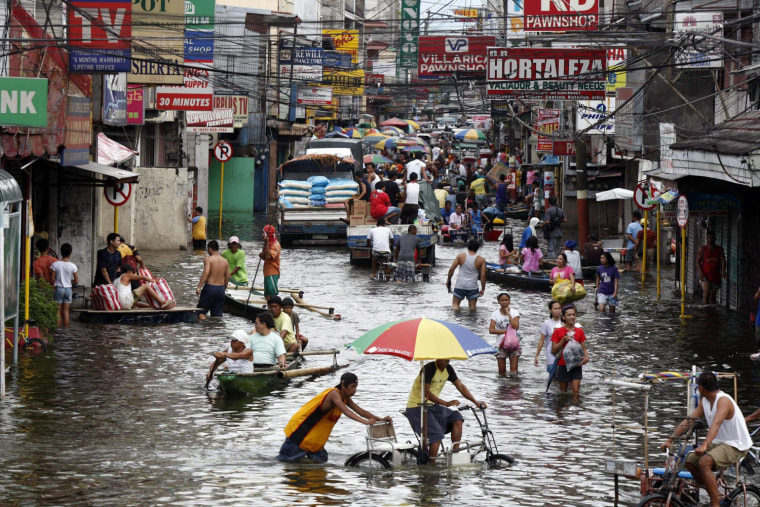 Image: Filipinos manuever in waist-deep floodwaters in Santa Cruz town, Laguna province, south of Manila