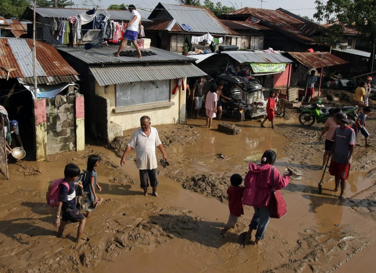 Image: A view of Filipino flood victims wlk on mud in the town of Rosales, Pangasinan province,