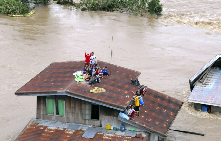 Image: Residents stay on the rooftop of their house half-submerged by floodwaters brought by Typhoon Parma in Pangasinan province