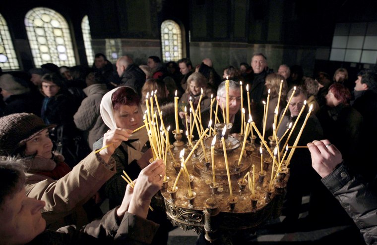 Image: People light candles during a Christmas Eve mass in Alexander Nevski Cathedral in Sofia