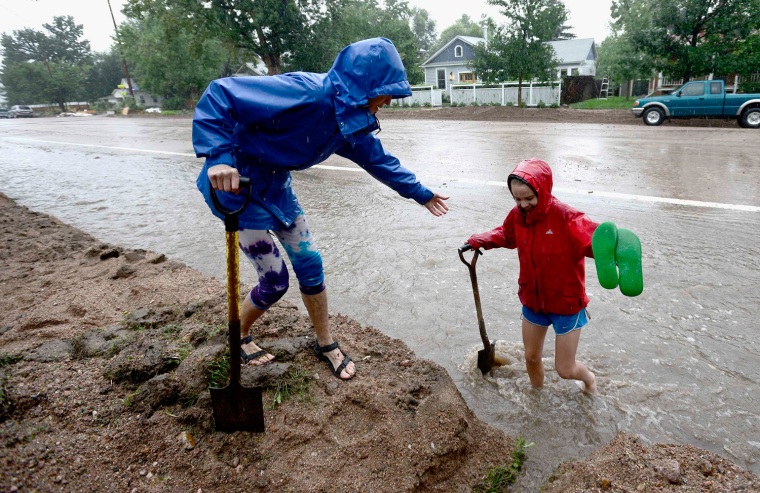 Image: Wendy Hoffenberg helps Sophia Cornell up the side walk as rain starts getting heavier in Boulder, Colorado