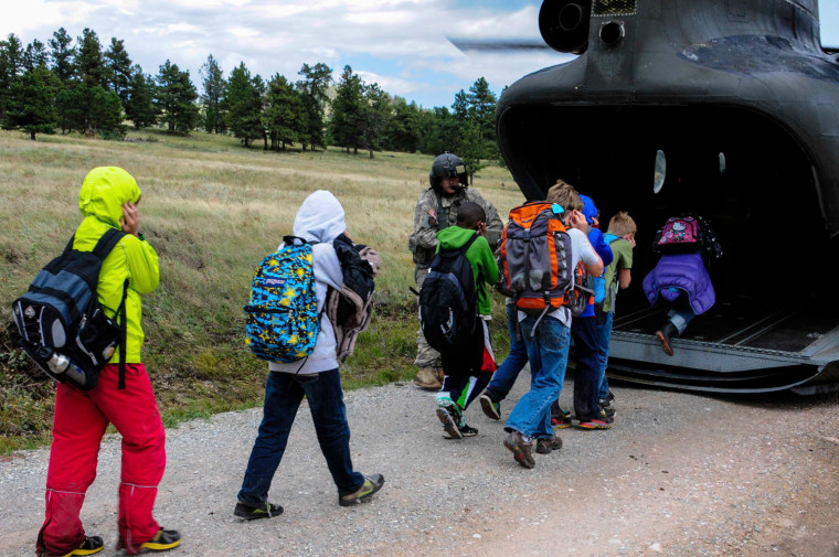 Image: Handout photo of children from Cal-Wood Education Center in Jamestown, Colorado boarding rescue helicopter after severe flooding shut down major roads leading out of town