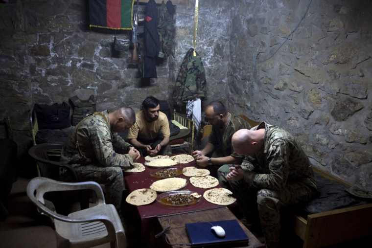 Two U.S. Marines, embedded with members of the Afghan national army (ANA), pray before a meal along with two Afghan soldiers at an outpost in the village of Kamu, Afghanistan.