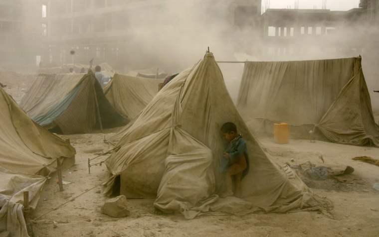 YEAR-2008 An Afghan refugee child hides from a dust storm behind a tent at a refugee camp in Kabul on October 7, 2008. Over a quarter million Afghans have returned home this year from Pakistan and Iran, many of them reportedly due to economic and security uncertainties faced in exile, the United Nations said.  AFP PHOTO/ Manpreet ROMANA (Photo credit should read MANPREET ROMANA/AFP/Getty Images)